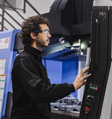 A focused view of a complex control panel of metalworking CNC milling machine, with an engineer meticulously working on machinery. Industrial work concept.